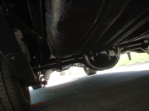 1970 Ford Torino - The underside of a vehicle shows the rear axle assembly, fuel tank, and suspension components.