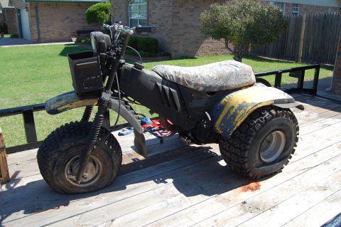 1985 Ford Ranger - This three-wheeled ATV, with a camouflage seat and yellow body, is parked on a wooden trailer.