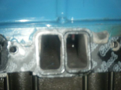 1979 Chevrolet Camaro - The image shows two intake ports on an engine's intake manifold, with a blue painted surface visible above.