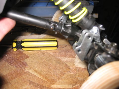 2010 Ford Pickup - Close-up of a drive shaft and suspension components, with a screwdriver nearby.