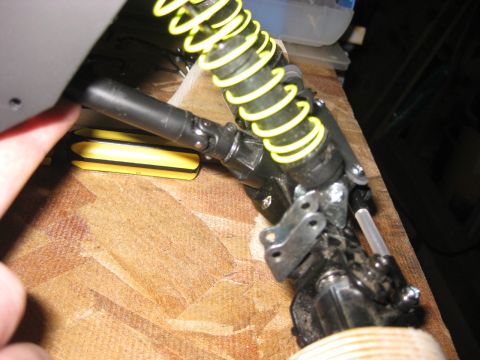 2010 Ford Pickup - Close-up view of a yellow coilover suspension component, likely from an RC car or similar model, showing mechanical linkages and a drive sh…