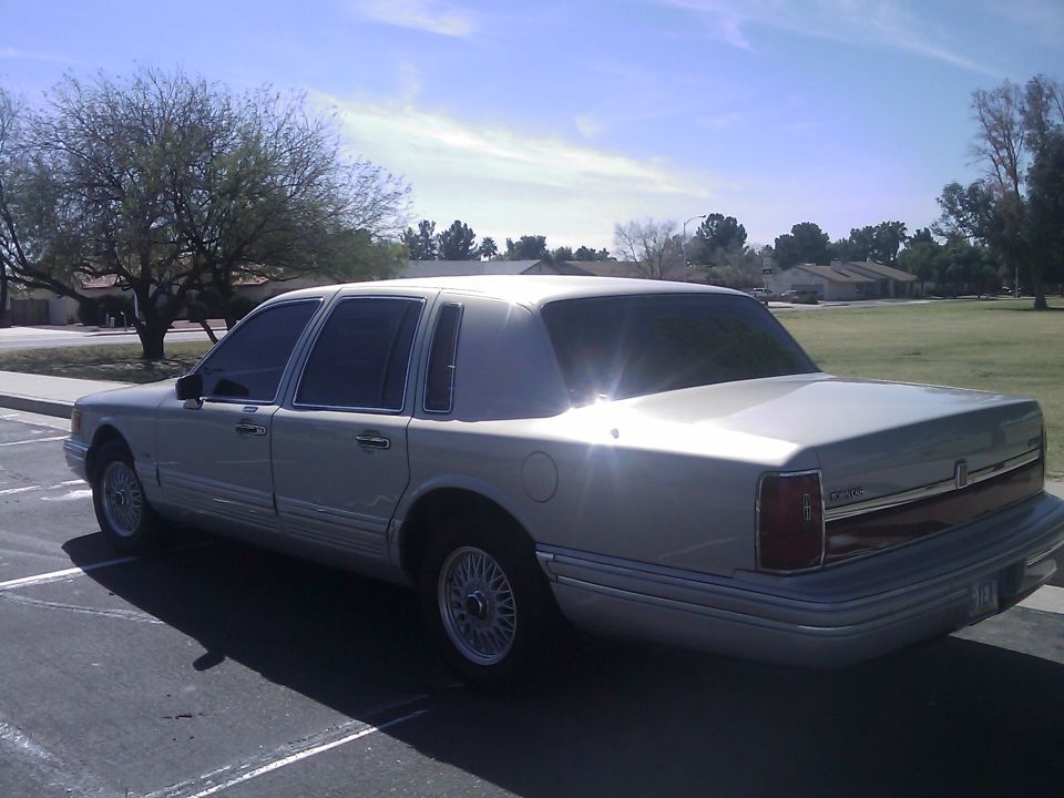 Silver Lincoln Town Car sedan, rear 3/4 view in a parking lot