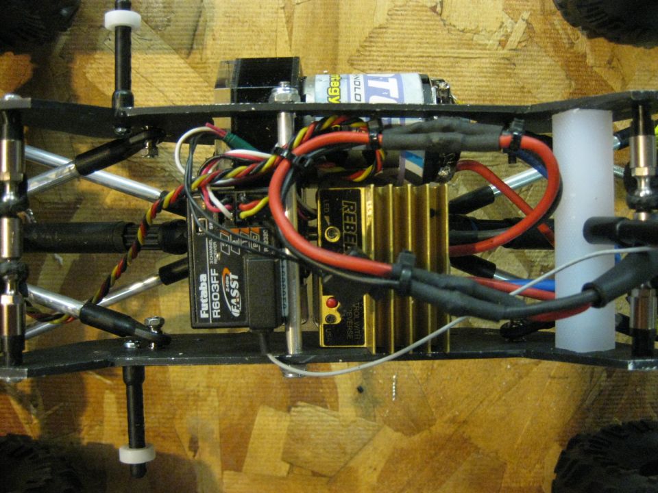 Close-up of remote control car electronics: Futaba R603FF receiver, gold heatsink, battery, and wiring
