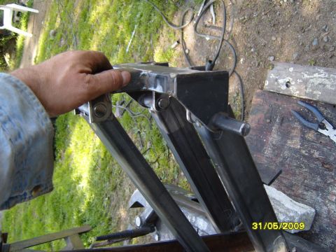 1989 Ford Bronco - A close-up view of a metal frame part, possibly a component for a vehicle, with a hand holding it.