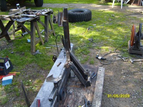 1989 Ford Bronco - Metal fabrication parts and tools are laid out on a lawn, with a large tire and chop saw visible.