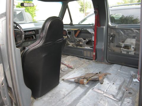 1986 Ford Bronco - Interior view of a 1986 Ford Bronco with door panels removed and floor stripped.