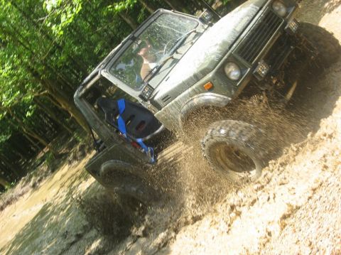1987 Suzuki Samurai - This 1987 Suzuki Samurai navigates a muddy trail, kicking up dirt and water.