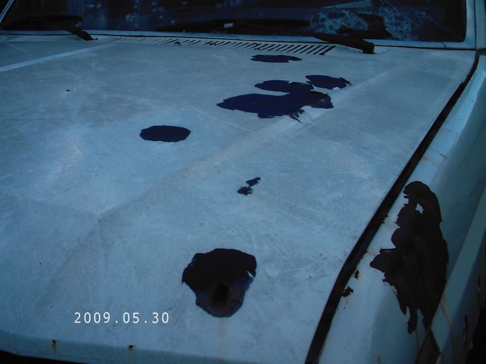 White vehicle hood with dark fluid stains and rust patches. Date stamp reads 2009.05.30