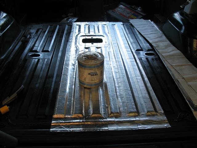 Vehicle floor pan lined with reflective sound-deadening mat and a can of Peel & Seal on top