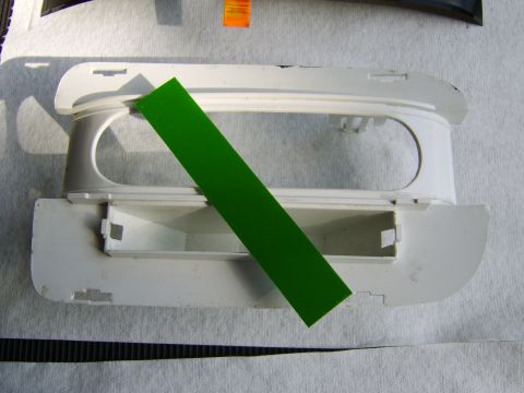 1996 Mercury Grand Marquis - A white plastic automotive interior trim piece, likely a center console or overhead component, lies on a gray padded surface with a diagona…