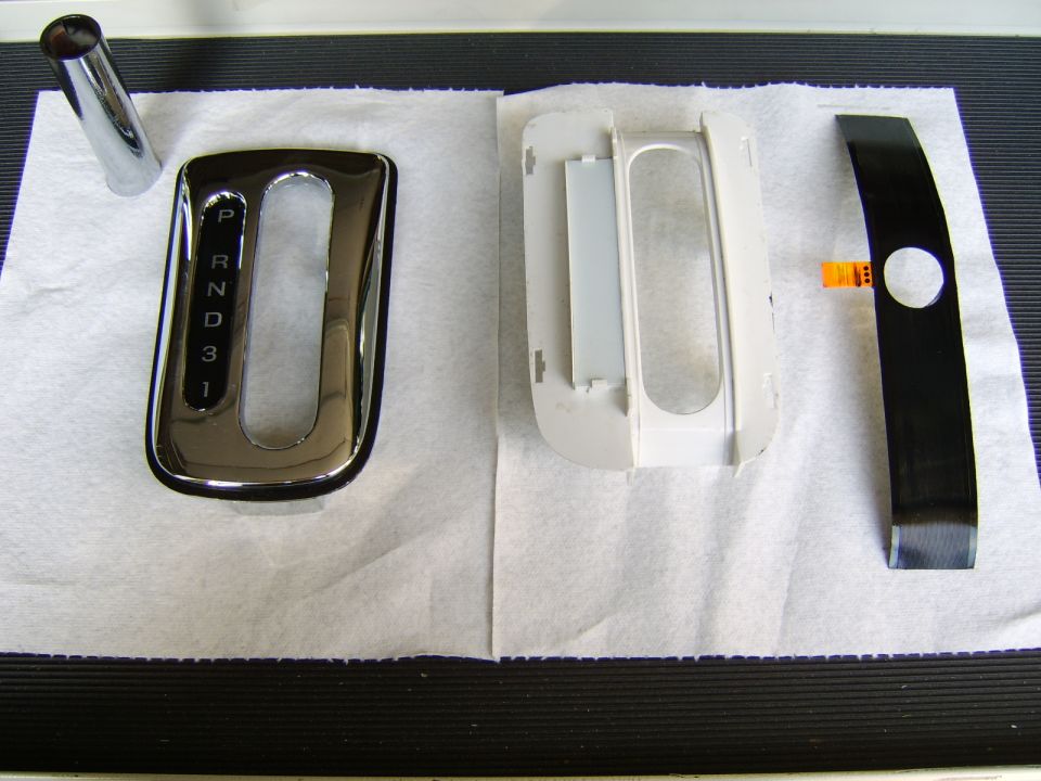 Chrome PRND shifter gate, white backing frame, and black trim panel on paper.