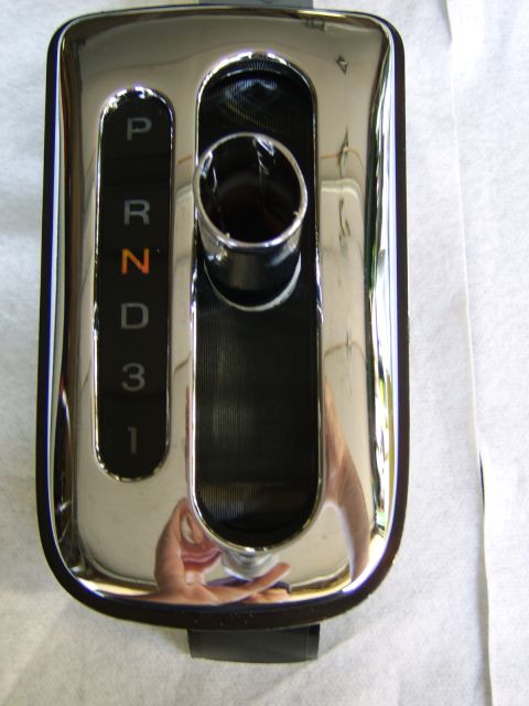 1996 Mercury Grand Marquis - Close-up of a chrome automatic gear shifter bezel with the PRND31 gate pattern illuminated, the 'N' highlighted in orange. The polished chr…