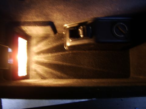 1996 Mercury Grand Marquis - A dark, blurry interior close-up of a center console or dashboard area, showing a rotary knob on the right and an illuminated red/white lig…