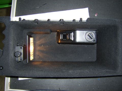 1996 Mercury Grand Marquis - Close-up of a black plastic console piece set in gray foam packaging, containing a rocker switch marked "OFF," a small rotary dimmer knob w…