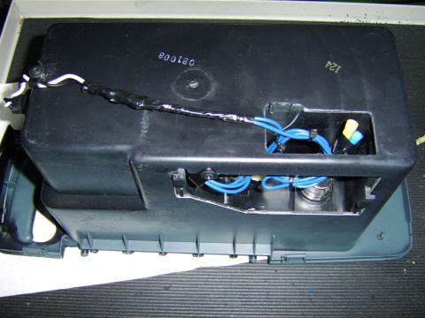 1996 Mercury Grand Marquis - A black plastic automotive component, likely an airbox or electronics housing, shown open on a ribbed mat with blue vacuum/wiring hoses, a…
