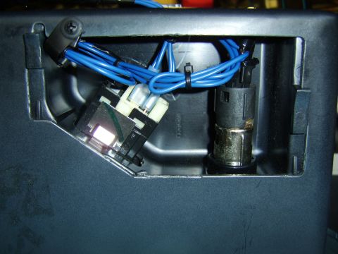 1996 Mercury Grand Marquis - Close-up of an automotive interior console opening showing blue-jacketed wiring, a white multi-pin electrical connector, an illuminated swi…