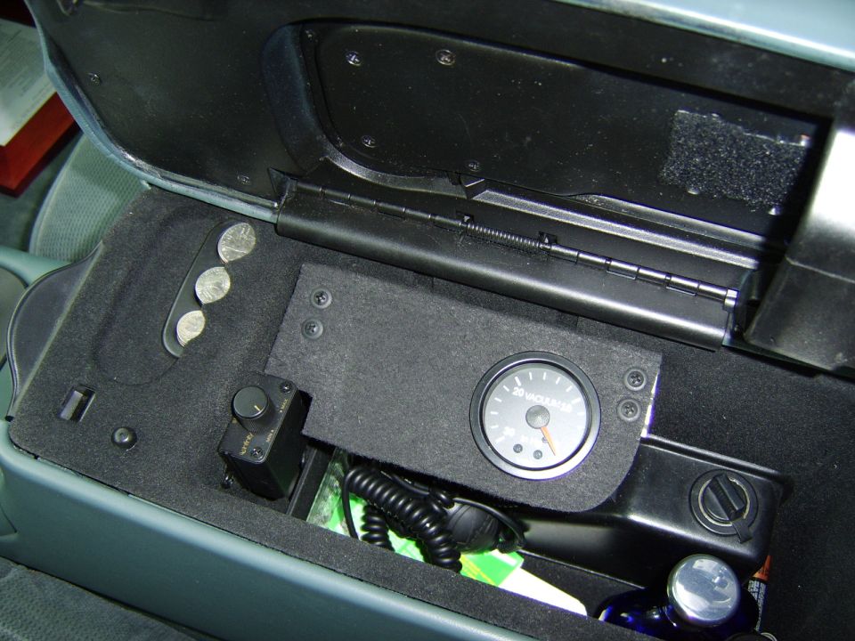Center console with mounted vacuum gauge, knob, coiled cord and coins in black felt-lined tray