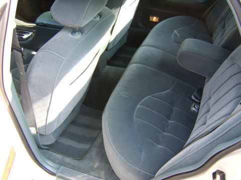 1996 Mercury Grand Marquis - Interior view of a sedan's rear seating area showing dark blue/gray cloth upholstered bench and folded front seatbacks, with matching carpe…