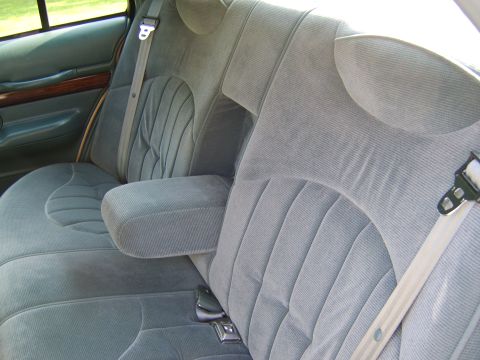 1996 Mercury Grand Marquis - Interior view of the rear bench seat upholstered in gray cloth, showing the seat cushions, seatback, folding armrest, and seat belts with b…