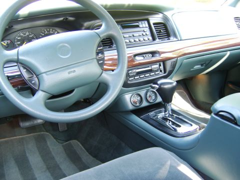 1996 Mercury Grand Marquis - Interior of a Mercury sedan with gray dash, woodgrain trim, factory radio, dual aftermarket gauges and a column or console automatic shifte…