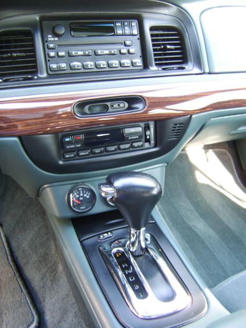 1996 Mercury Grand Marquis - Interior center console and dash of a Mercury Grand Marquis showing a cassette/CD radio, climate controls with wood-grain trim, a leather s…
