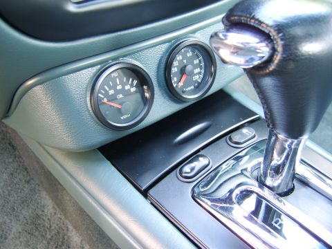 1996 Mercury Grand Marquis - Close-up of a center console area showing two round VDO gauges (an oil pressure gauge reading PSI and a temperature gauge in °F) mounted in…