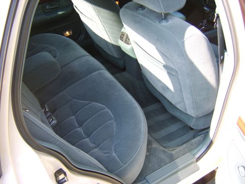 1996 Mercury Grand Marquis - Interior view of the rear passenger area showing gray/blue cloth upholstered seats, with the folded-down front seatbacks visible and gray c…