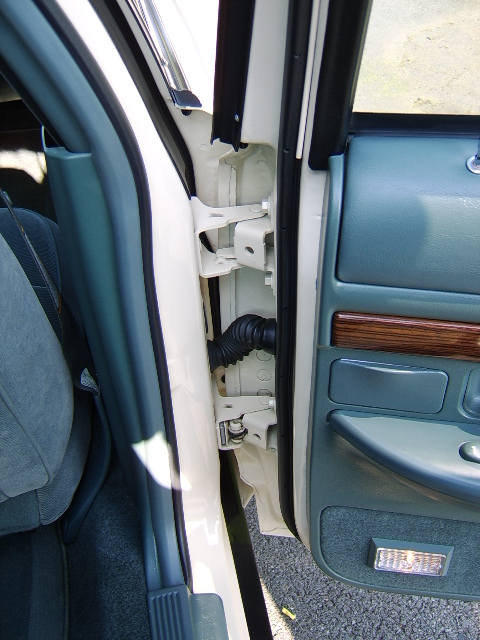 1996 Mercury Grand Marquis - Door jamb detail showing exposed latch hardware and wiring conduit, with teal leather door panel and wood trim visible.