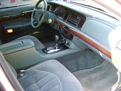 1996 Mercury Grand Marquis - Interior view from the passenger side of a gray/green cloth and leather cabin, showing the center console with a chrome-accented automatic…