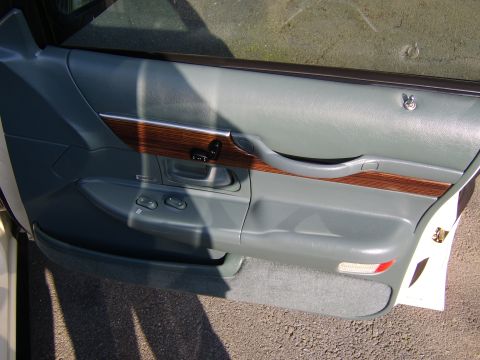 1996 Mercury Grand Marquis - Interior view of a gray driver's-side front door panel with wood-grain trim accent, showing power window and lock switches, a door handle,…