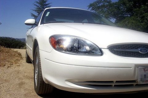 2000 Ford Taurus - White 2000 Ford Taurus front view on a dirt road with trees in the background.