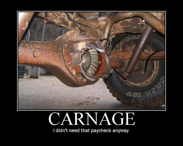 Close-up of a damaged rear differential with exposed gears and a tire with 'BAJA MT' visible