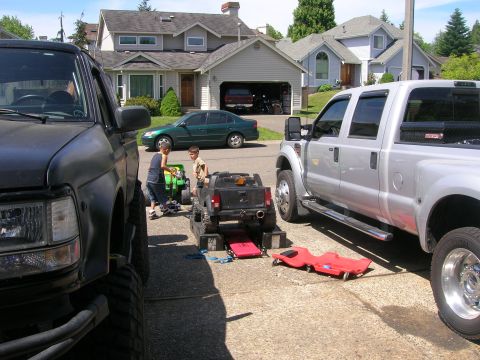 1996 Ford Bronco - Children play with toy trucks on a driveway next to full-sized vehicles.