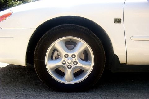 2000 Ford Taurus - Close-up of the front wheel and fender of a white 2000 Ford Taurus, a '24V DOHC' badge.