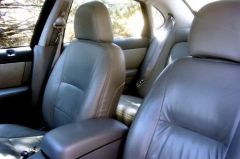 2000 Ford Taurus - The interior of a car shows gray leather seats and seatbelts, with sunlight filtering through the windows.