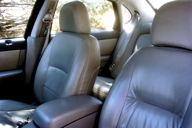 Gray leather car interior with front and rear seats visible, armrest, and seatbelts
