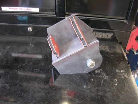 1996 Ford Bronco - A fabricated metal bracket with a bolt and what appear to be rubber dampeners is shown on a workbench.