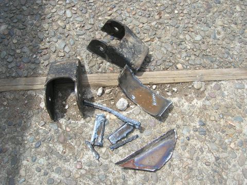 1996 Ford Bronco - Several pieces of broken metal, possibly from a vehicle repair, lie scattered on the ground.