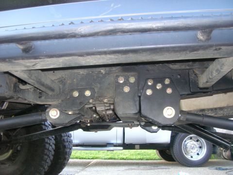 1996 Ford Bronco - Custom radius arm mounts are installed on the undercarriage of a vehicle, with a second truck partially visible in the background.