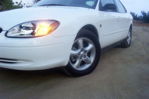 2000 Ford Taurus - The front passenger side of a white 2000 Ford Taurus sedan is shown at an angle, with the turn signal illuminated.