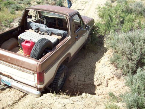 1985 Ford Bronco - This older model Ford Bronco is navigating a challenging off-road terrain, getting stuck in a dirt ditch.
