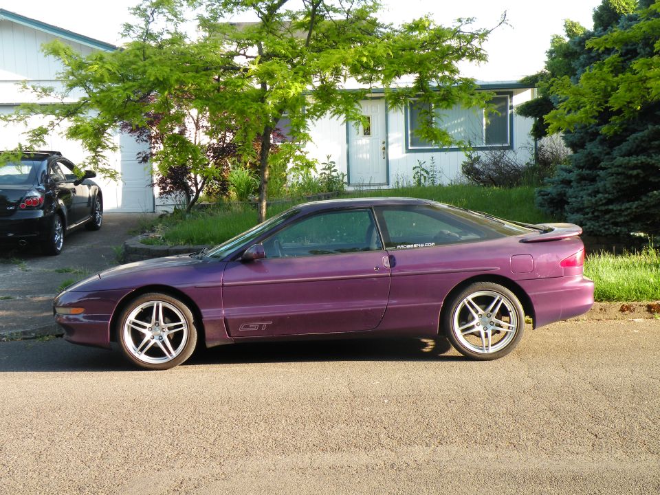 Purple Ford Probe GT coupe in side profile on silver five-spoke wheels at a curb