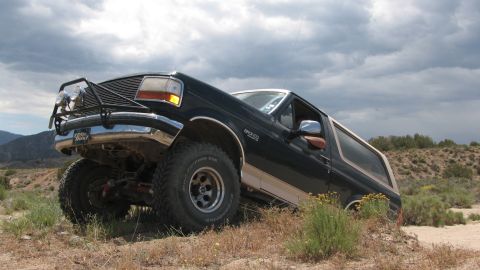 1996 Ford C-350 (Centurion Conversions) - Ford Bronco navigates rough terrain under a cloudy sky.