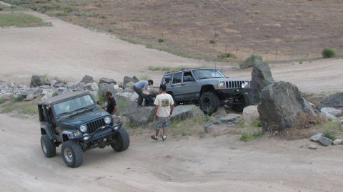 1996 Ford C-350 (Centurion Conversions) - Off-roading scene with two Jeeps and several people on a dirt and rock-filled trail.