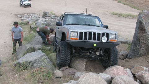 1996 Ford C-350 (Centurion Conversions) - A modified Jeep Cherokee XJ navigates a rocky obstacle course with assistance from onlookers.