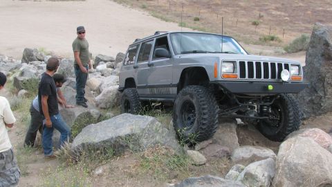1996 Ford C-350 (Centurion Conversions) - A modified Jeep Cherokee XJ tackles a rocky trail, demonstrating its off-road capabilities.