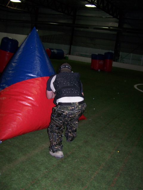 1986 Ford Bronco - A paintball player takes cover behind a large inflatable barrier during a game on an indoor field.