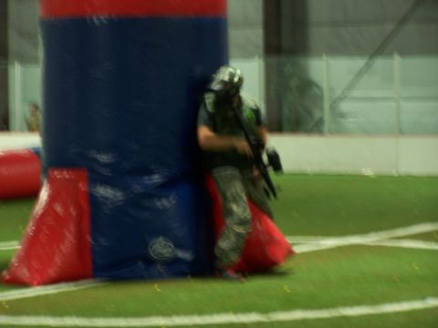 1986 Ford Bronco - A paintball player takes cover behind an inflatable barrier during a game on an indoor turf field.
