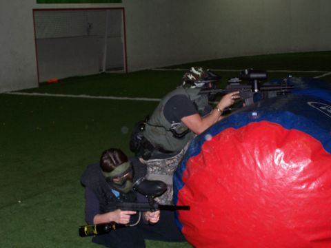 1986 Ford Bronco - Players take cover behind a large inflatable obstacle during an indoor paintball game.