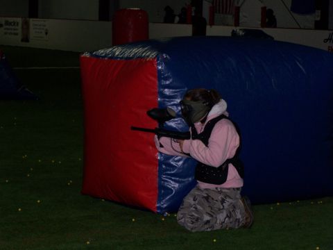 1986 Ford Bronco - A person kneels behind inflatable barriers, aiming a paintball gun while wearing protective gear.